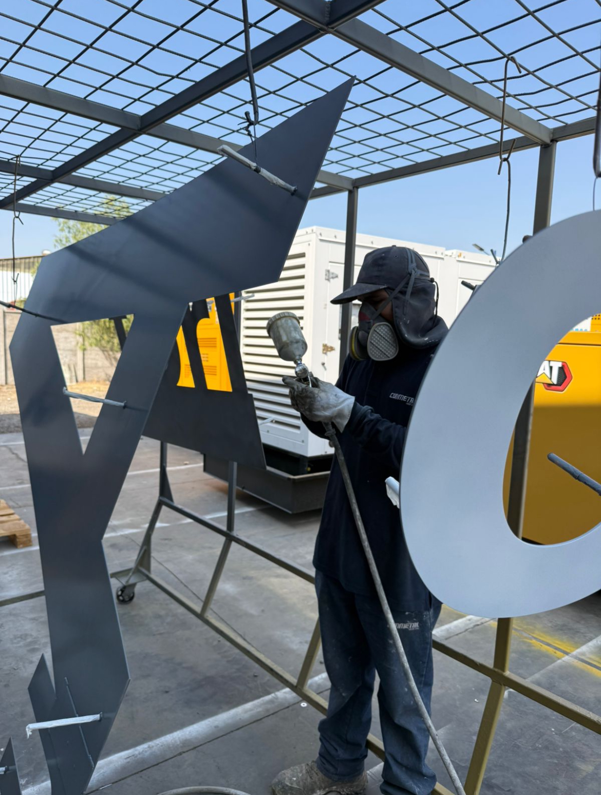 Spray painting large metal sign letters in the workshop